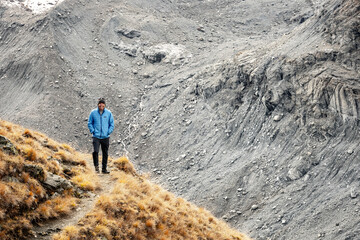 Obraz premium Hiker In Blue Coat Walks Around Corner Of Trail