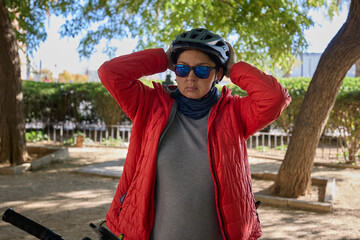 Close-up of woman adjusting protective bicycle helmet in a park before cycling.