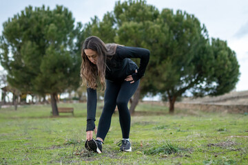Woman stretching outdoors in park, warming up for a fitness workout, actively improving health and physical well-being