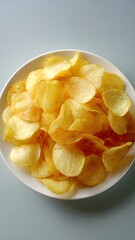 Crispy Potato Chips in White Bowl on Minimal Background &ndash; Snack Food Concept