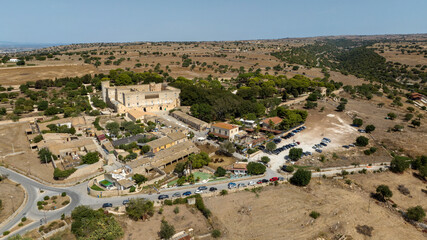 Obraz premium Aerial view of Donnafugata Castle, located in the countryside in the province of Ragusa, Sicily, Italy. It is a very large building in Neo-Classical and Neo-Gothic styles. A avenue leads to the entry.