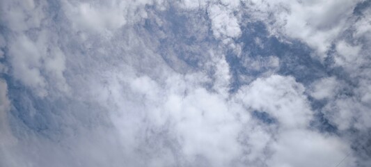 Background with clouds on blue sky. Sky view. Beautiful sunny sky. Clouds on blue sky. Sun shining through the puffy clouds.