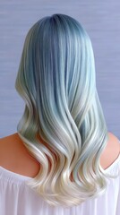 Naklejka premium Back view of a woman with long, wavy ombre hair transitioning from blue at the roots to blonde at the tips. The hair is styled with soft curls. She is wearing a