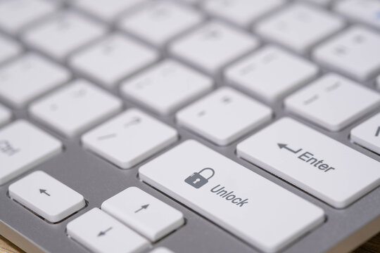A close-up keyboard with an unlock key and open padlock icon represents access control, cybersecurity, data protection, login permission, and secure system management in the digital environment.