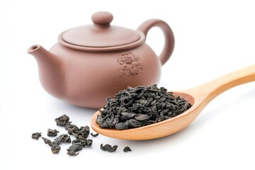 A traditional Chinese teapot with intricate designs and a wooden spoon filled with black tea leaves.