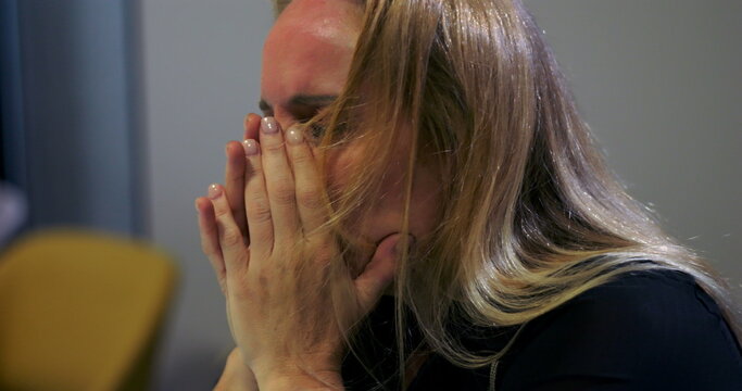 Close-up of stressed businesswoman covering face with hands in emotional breakdown, overwhelmed by workplace burnout and corporate pressure