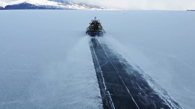 Aerial top down Hivus hovercrafts glide across endless winter ice of frozen Lake Baikal. Natural landscape, vast expanse UNESCO heritage site, amazing off-road adventure tourism Russia