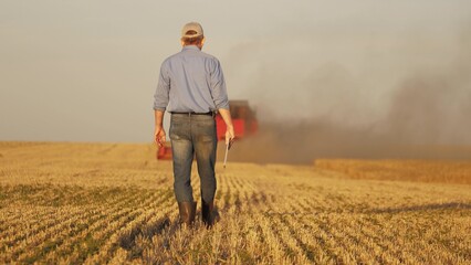 farmer working in wheat field, combine harvester ploughing in wheat field, agriculture tablet, enhancing decision making with data, revolutionizing agricultural practices, efficient resource