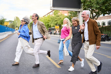 Senior friends running vigorously across city street