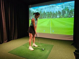 Indoor golf simulation activity with a player preparing to swing at a virtual driving range