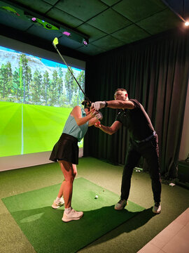 Golf lesson in a simulator studio with a coach and student improving swing technique concept