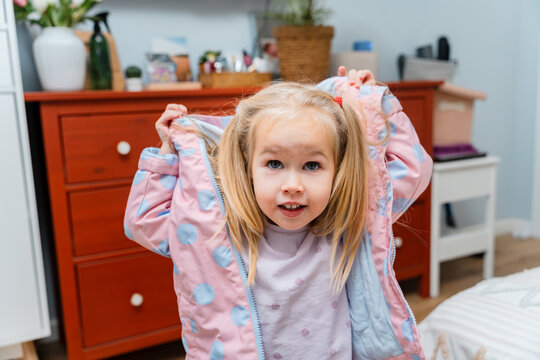 Caucasian three-year-old child girl puts on a jacket by herself