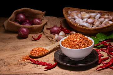Chili powder in a white cup and wooden spoon, garlic, shallots, spicy seasoning, spices for cooking.