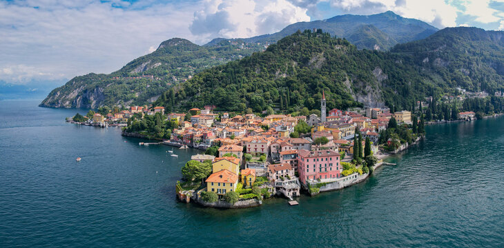 Aerial view of quaint buildings with terracotta roofs nestle against the deep blue waters of Lake Como, surrounded by lush green mountains, Bellagio, Lombardy, Italy.