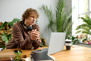 Creative young man engaged with laptop in a bright workspace filled with plants and wood
