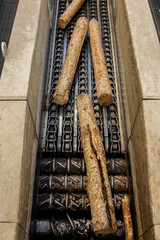 Wood logs being transported on a heavy-duty industrial conveyor inside a timber or pulp processing facility. The machinery moves raw wood for further processing.