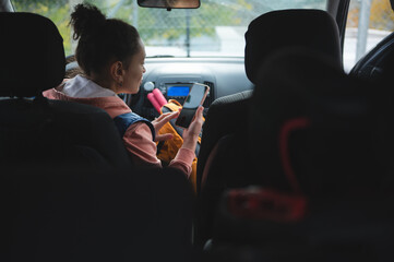 Young Woman in Car Backseat Using Smartphone During Road Trip With Friends