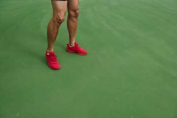 Athlete in Red Shoes Stands on Green Tennis Court Surface During Training