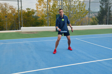 Obraz premium Athlete Playing Paddle Tennis On Blue Court With Focused Expression