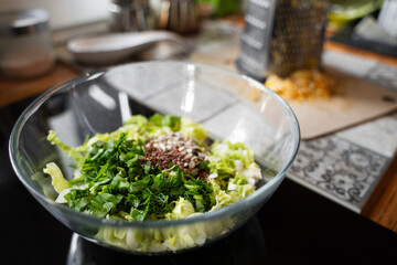 Glass bowl with chopped greens and seed mix on kitchen counter during home cooking, healthy lifestyle ingredients and plant-based food preparation