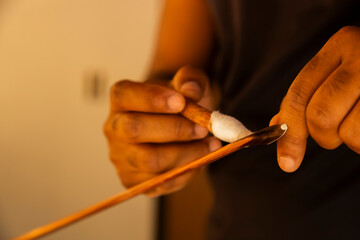 Violin making by hand bow. Close-up of an artisan&rsquo;s hands sanding or shaping a tool handle on a workbench. 