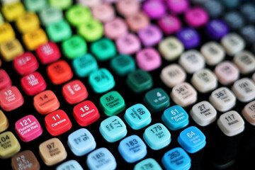Top view of many colorful artistic markers with different color names on the lids