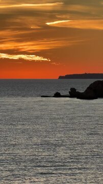 Beautiful sandy beach with red rocks and cliffs. Sunset at dusk with shallow waves on the Atlantic coast in Praia do Po&ccedil;o Velho, Praia da Fal&eacute;sia, Algarve, Portugal