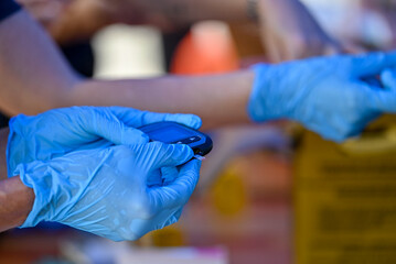 Nurse pricking a patient's finger to perform a blood glucose test.