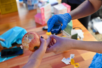 Nurse pricking a patient's finger to perform a blood glucose test.