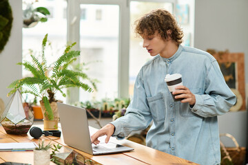 Young creative man working on laptop while enjoying coffee in a cozy, green space