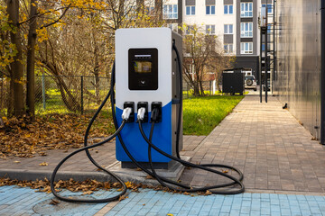 Electric vehicle charging station with multiple cables located outdoors in urban area near...