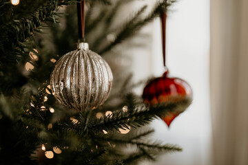 Elegant Silver and Red Christmas Ornaments on Fir Tree with Warm Lights