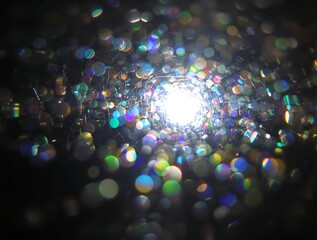 Mesmerizing tunnel of shimmering light orbs creates a vibrant, abstract bokeh effect, reminiscent of a kaleidoscopic dream