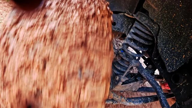 A close-up view of a muddy off-road tire spinning as the suspension flexes over rough terrain. Dynamic automotive footage showing mud splashes, wheel movement, and rugged off-road performance.