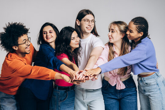 Diverse group of young people stacking hands, showing unity and teamwork
