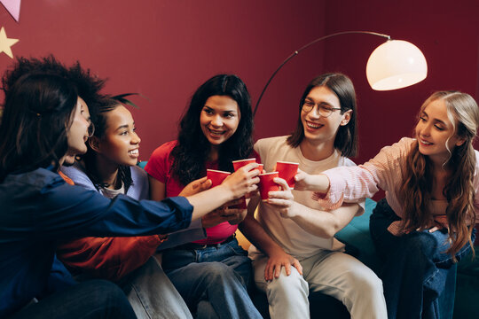 Group of diverse smiling friends toasting at a party, enjoying a fun time together