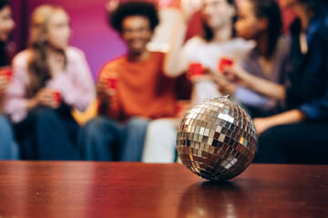 Disco ball on table with friends enjoying a party in background