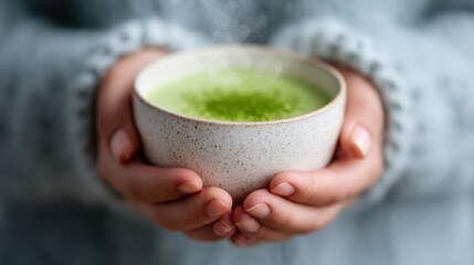 A serene moment captured with hands cradling a bowl of warm matcha tea, showing steam rising and inviting a sense of tranquility and comfort amidst life's hustle.