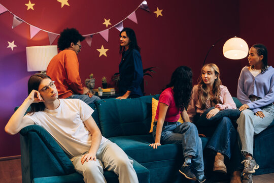 Young man feeling awkward and bored at a social party with friends