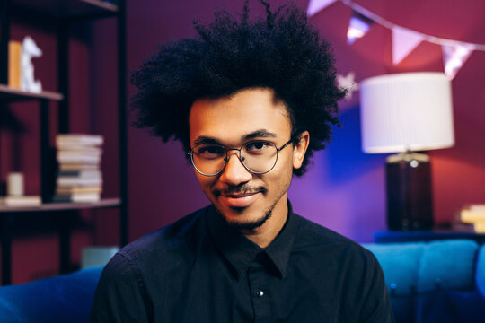 Smiling young man with glasses and afro hair celebrating a casual party at home