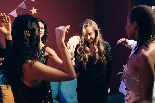 Young woman feeling shy and hesitant at a vibrant social party with friends