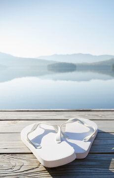 Flip flop sandals on dock by calm lake