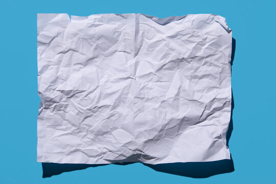 Blank crumpled paper on blue background