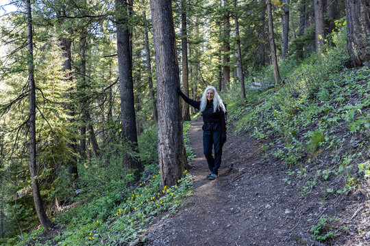 Portrait of smiling woman standing on footpath in forest