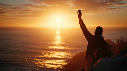 Silhouette of a person on a coastal cliff at sunset, raising an arm toward the sun over the sea. Concept Silhouette, Coastal cliff, Sunset, Sea, Dramatic pose