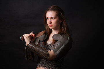 Obraz premium Portrait of a young woman, fantasy warrior in armor with a sword in her hands isolated on a dark background.