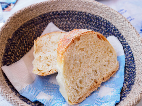Woven basket with slices of fresh, crusty, white bread on napkin