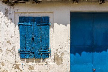 Weathered blue wooden shutters and door against white wall