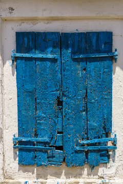 Weathered blue wooden shutters against white wall