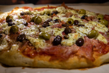 pizza fatta in casa con olive verdi e nere, prosciutto cotto, mozzarella e pomodoro